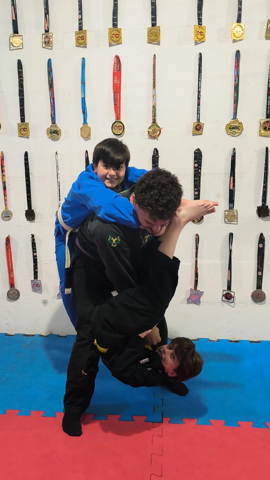Professor Helton brincando com dois alunos no tatame da Vanguard